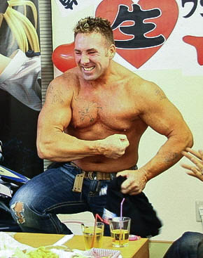A real photograph of Billy Herrington smiling at a fan event