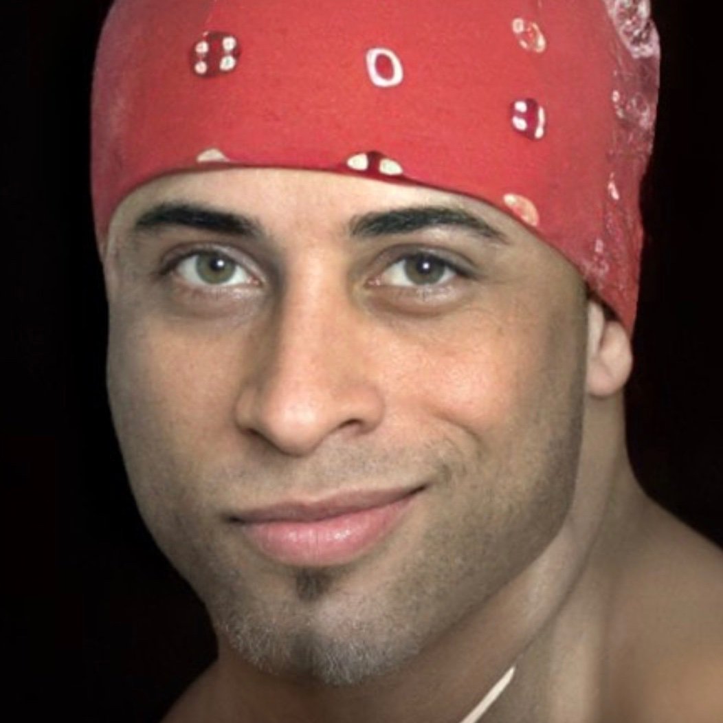 A real photograph of Ricardo Milos wearing his red bandana